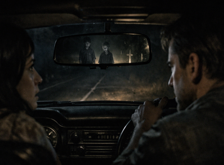 Pareja viendo a dos niños fantasma por el espejo retrovisor